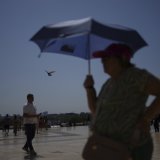 Un touriste s'abrite du soleil avec une ombrelle, sur le Trocadero à Paris, lors d'un épisode caniculaire de juillet. (image d'illustration) KEYSTONE/AP/CHRISTOPHE ENA
